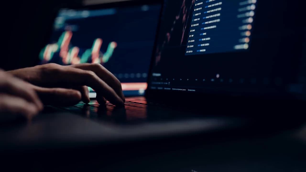 Hands working on a laptop showing financial charts