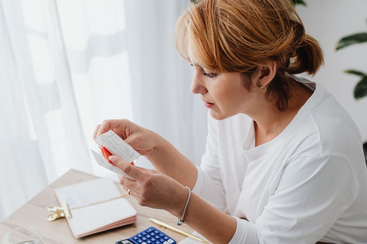 Debt Settlement Programs — woman calculating a budget with receipts
