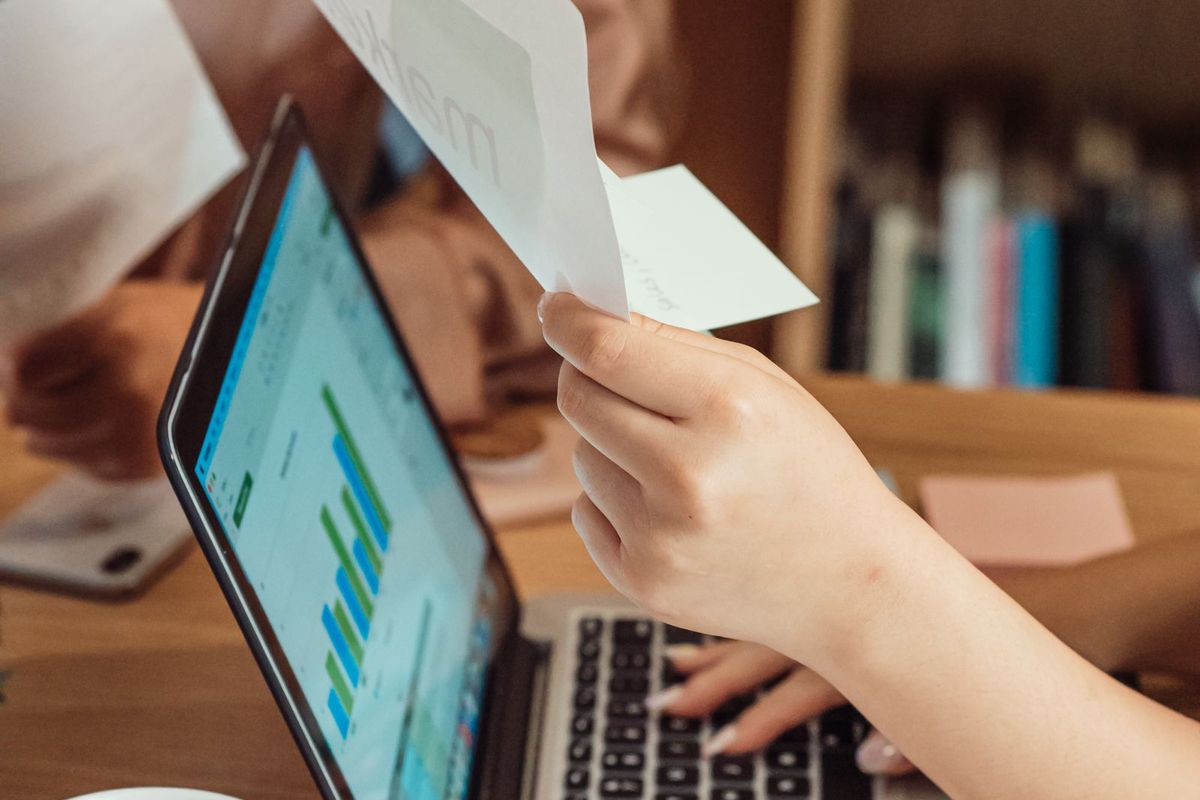 Debt Consolidation Programs — reviewing a paper beside a laptop