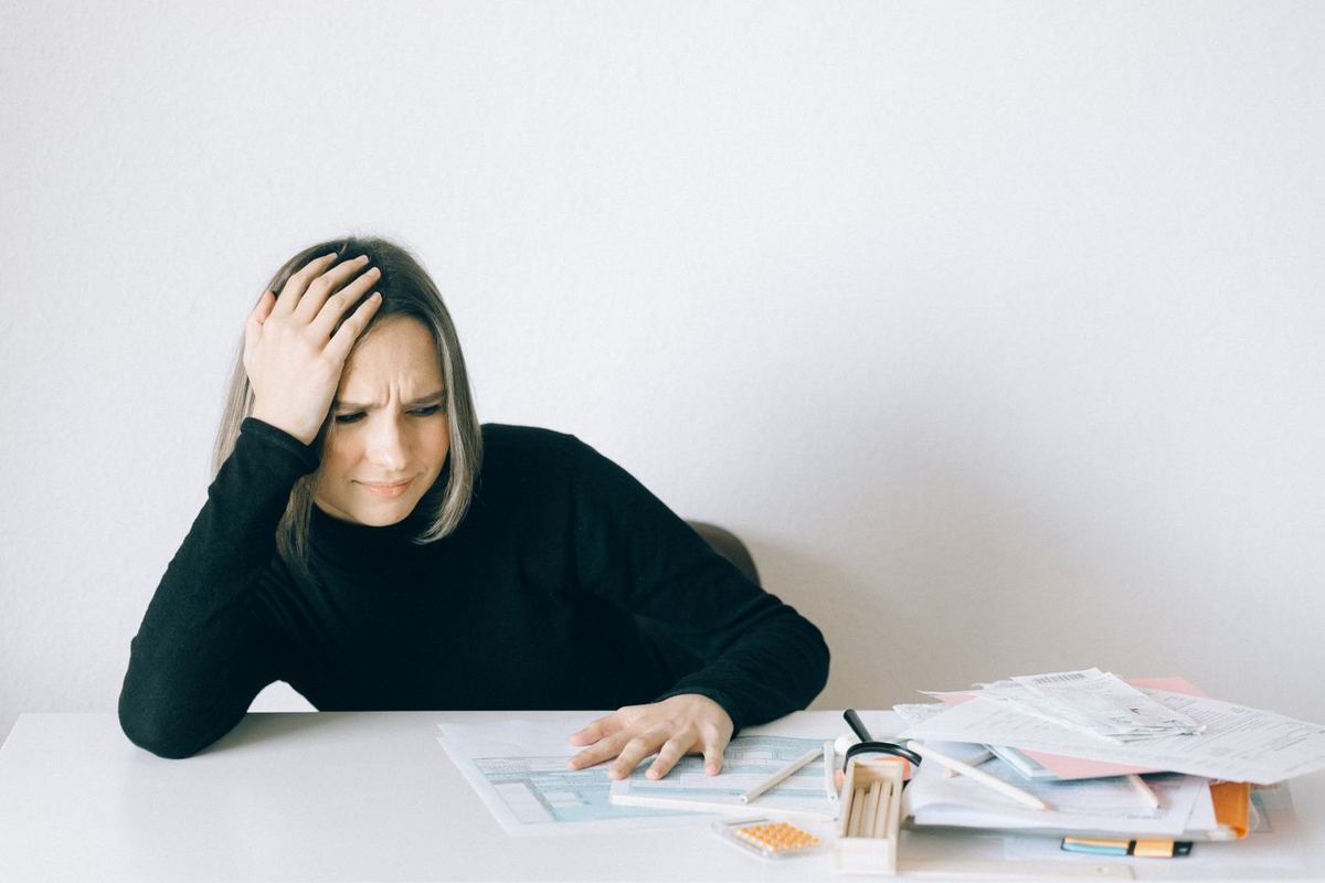 Debt Settlement Programs — woman reviewing a stack of bills